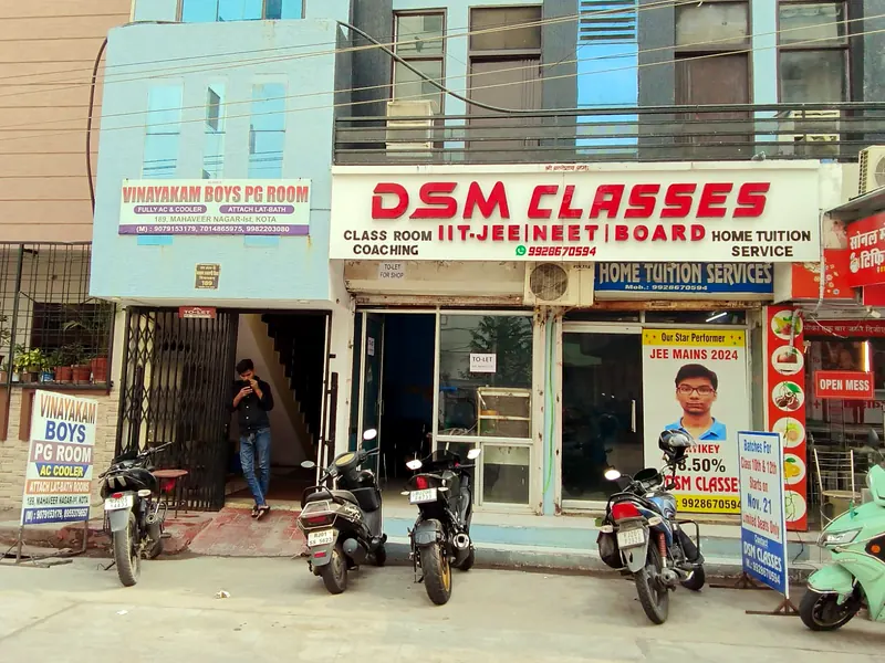 DSM Classes building from the street, with the signboard above the entrance and Vinayakam Boys PG Room next door